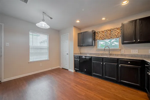 a kitchen with stainless steel appliances granite countertop wooden cabinets a stove a sink and dishwasher with wooden floor