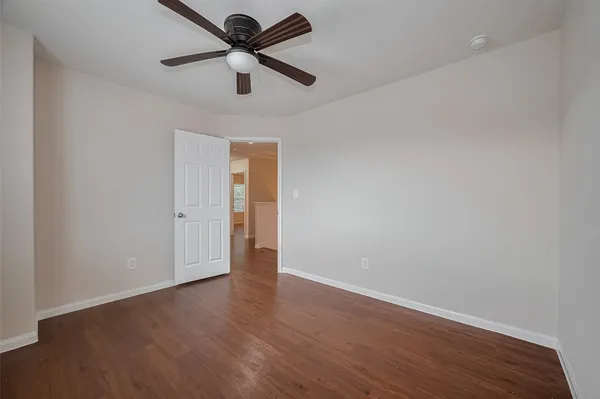 an empty room with wooden floor and ceiling fan