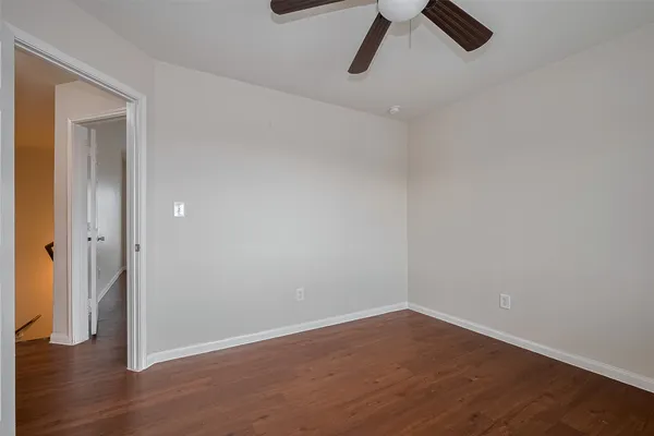 a view of a room with wooden floor and a ceiling fan