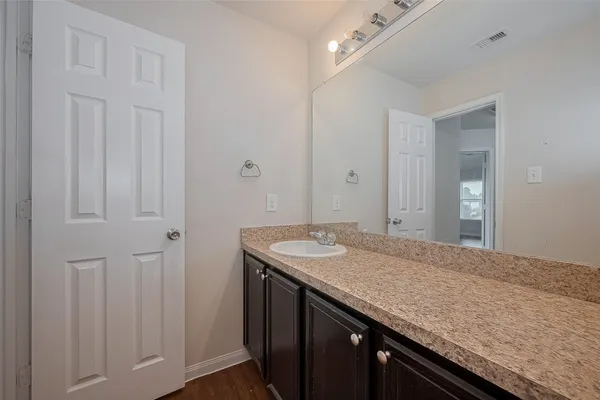 a bathroom with a granite countertop sink and white cabinets