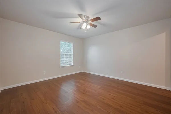 a view of an empty room with wooden floor and a window