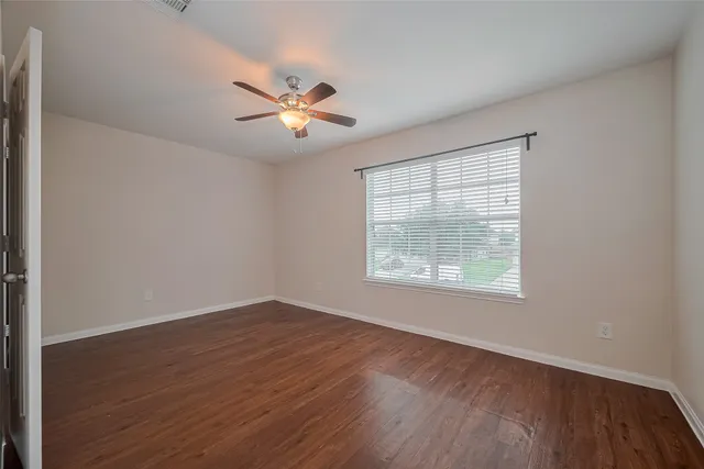 a view of an empty room with wooden floor and a window