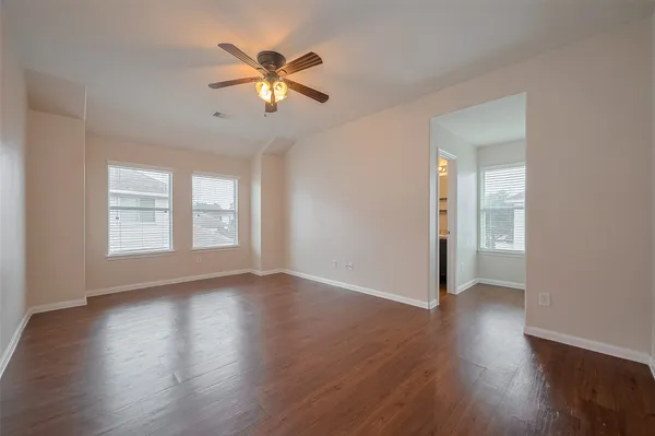 a view of an empty room with wooden floor and a window