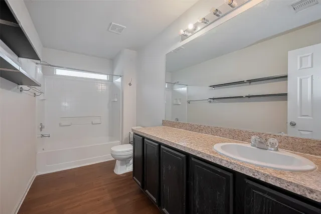 a bathroom with a granite countertop sink a toilet a shower and a mirror