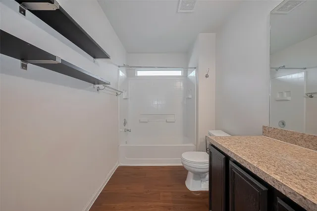 a bathroom with a granite countertop sink a toilet a mirror and shower