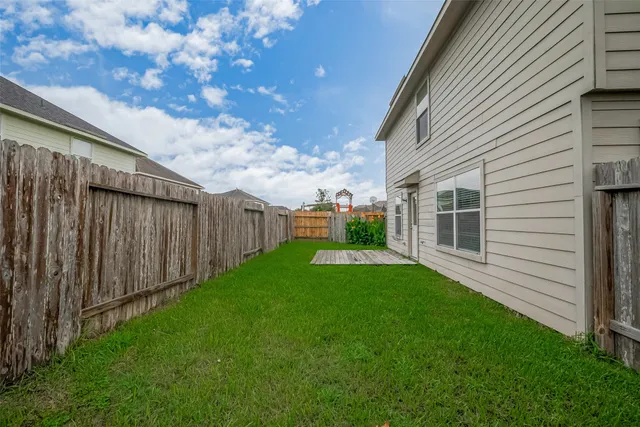 a view of backyard with barbeque grill potted plants and wooden fence