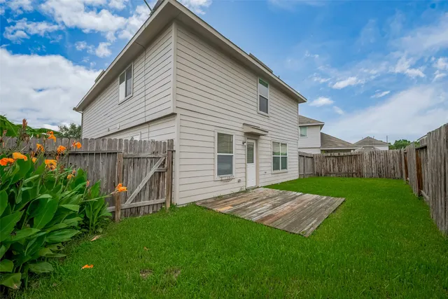 a view of a backyard with wooden fence and a bench