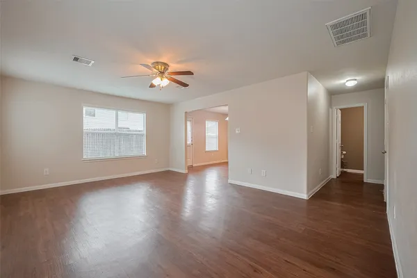a view of an empty room with window and wooden floor