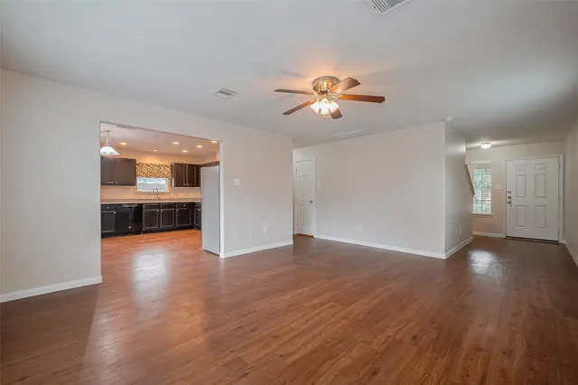 a view of an empty room with a kitchen and wooden floor