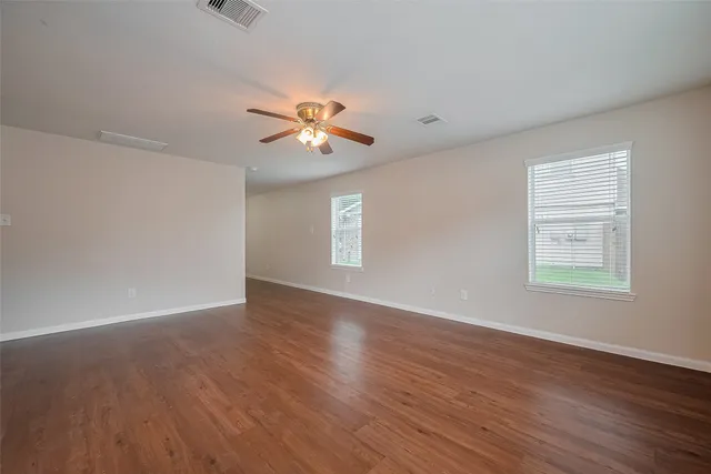 a view of an empty room with a window and wooden floor