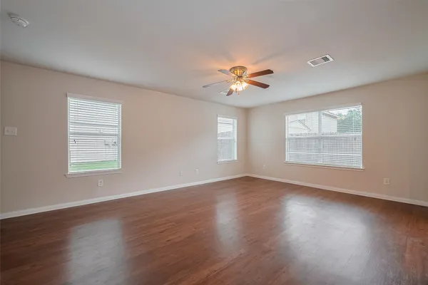 a view of an empty room with a window and wooden floor
