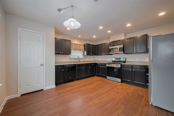 a kitchen with stainless steel appliances granite countertop a refrigerator a sink a stove and a wooden floors