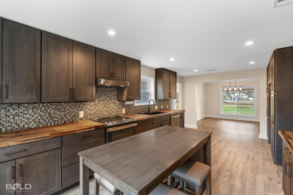 15 Lee Lane Haughton, LA 71037 - Photo 8 of 39 a kitchen with stainless steel appliances granite countertop a stove a refrigerator a sink a dining table and chairs with wooden floor