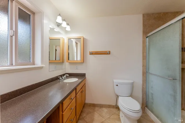 a bathroom with a granite countertop sink a toilet and mirror