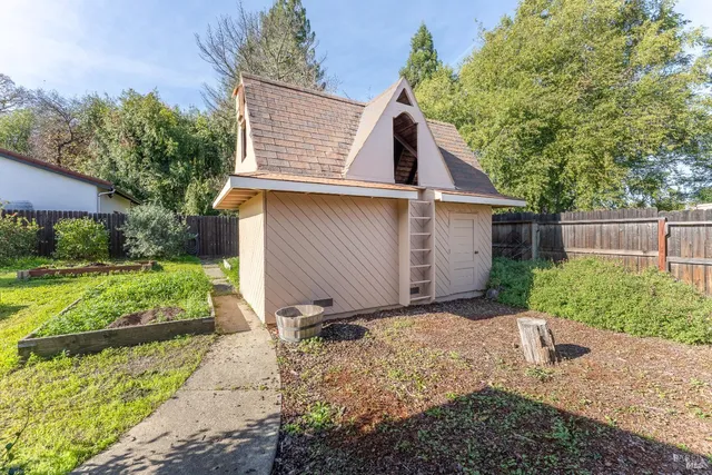 a view of backyard with large tree and wooden fence
