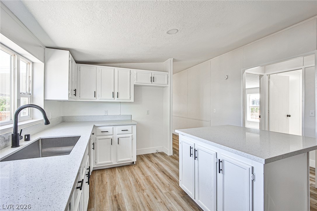 273 Aztec Lane Henderson, NV 89015 - Photo 3 of 28 A well-lit kitchen with sleek white cabinetry and a practical center island for culinary endeavors.