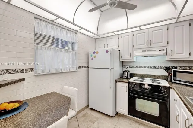 a kitchen with stainless steel appliances granite countertop a refrigerator a stove and a sink