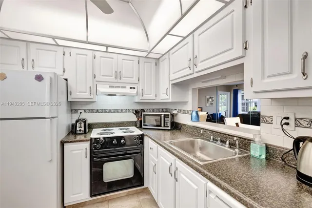a kitchen with granite countertop a sink stainless steel appliances and white cabinets