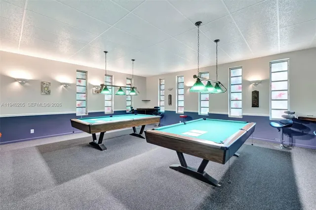 a living room with furniture pool table and windows