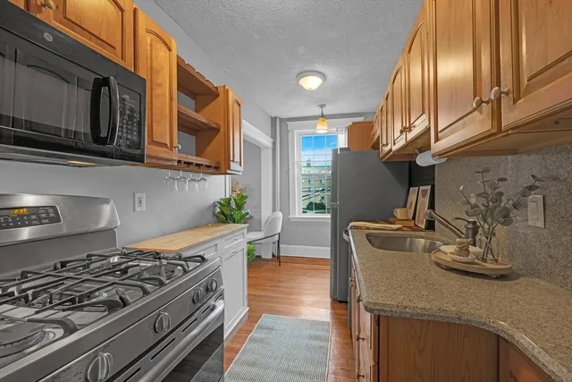 a kitchen with stainless steel appliances granite countertop a sink a stove and a wooden cabinets