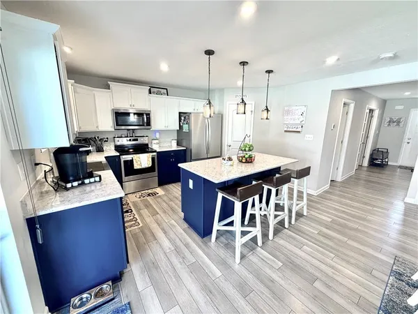 a view of kitchen with stainless steel appliances kitchen island granite countertop a refrigerator and microwave