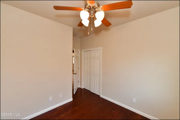 an empty room with wooden floor ceiling fan and window