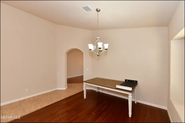 a view of a livingroom with a chandelier fan large windows and wooden floor