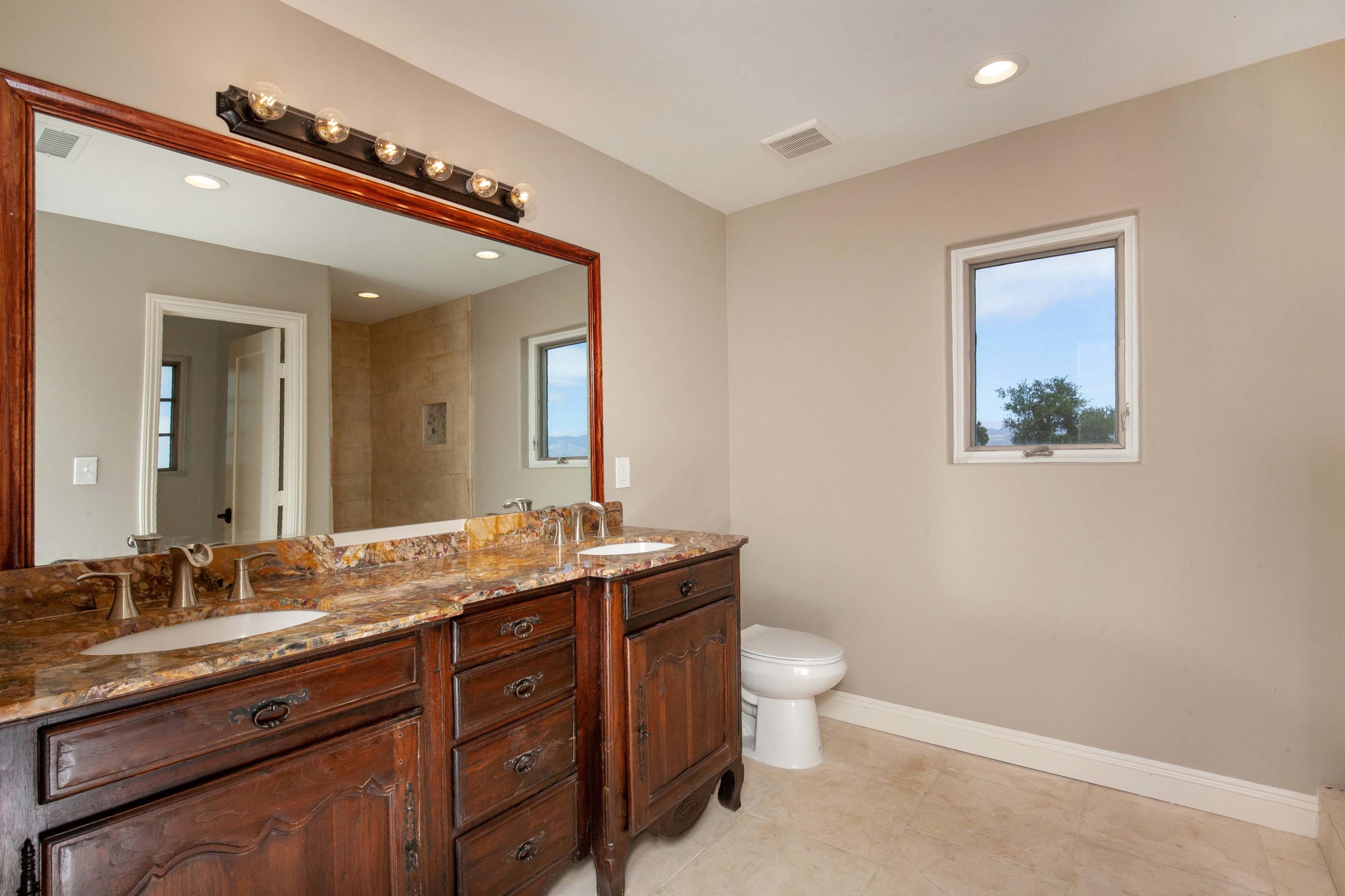 47383 Old Ridge Route Lake Hughes, CA 93532 - Photo 13 of 23 a spacious bathroom with a granite countertop sink a toilet and a mirror