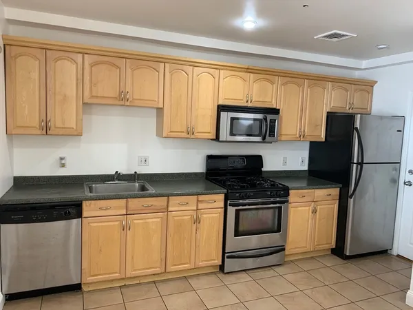 a kitchen with granite countertop white cabinets and stainless steel appliances