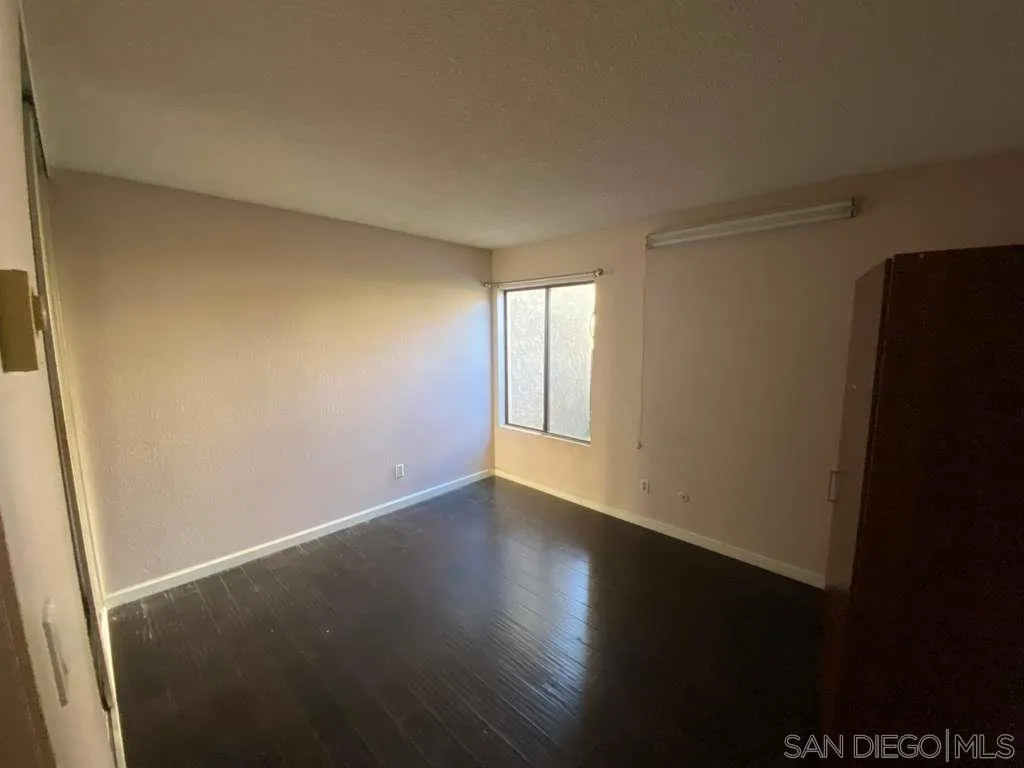 11174 Kelowna Road San Diego, CA 92126 - Photo 13 of 16 a view of an empty room with wooden floor and a window