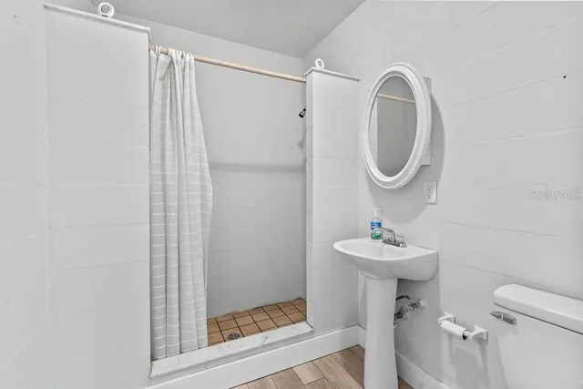 a bathroom with a sink a toilet and shower