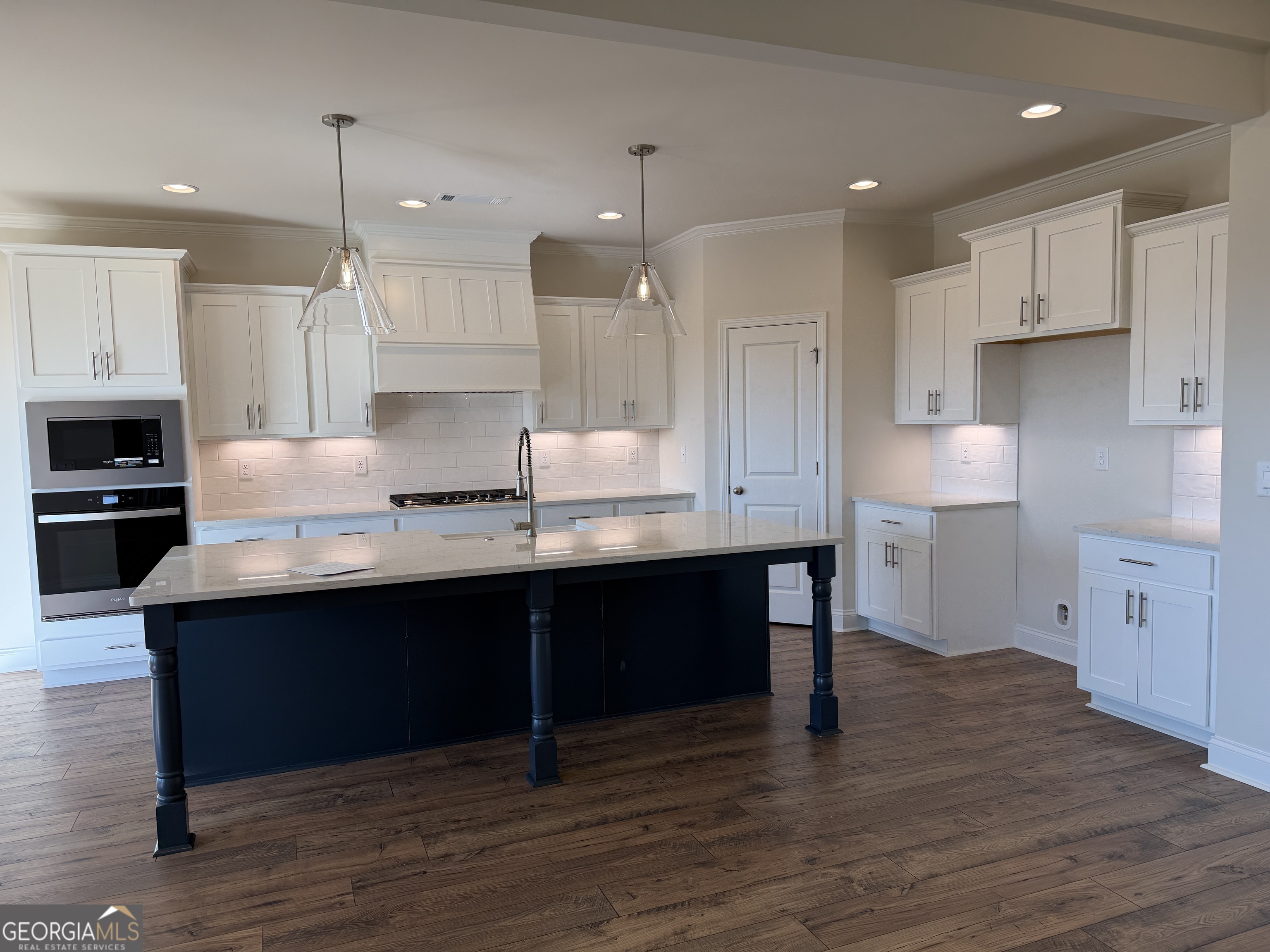 233 Oakdale Road, Unit 53 Jefferson, GA 30549 - Photo 12 of 64 Separate gas cook top w/ dramatic vent a hood, electric oven ideal for baking and microwave on the side, Under cabinet lighting, HUGE island with Porcelain farm sink, quartz counter tops, and plenty of space to entertain from.