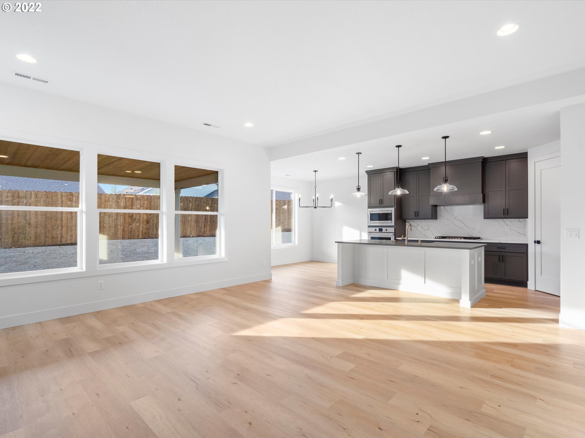 235 North 22nd Court Ridgefield, WA 98642 - Photo 8 of 25 a view of a kitchen with kitchen island a sink wooden floor and a large window