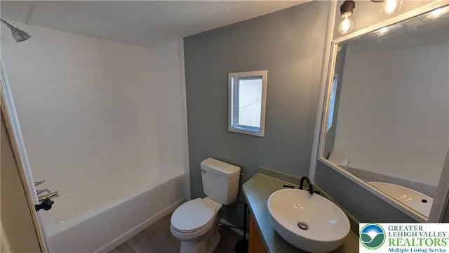 a white toilet sitting next to a bathroom sink and vanity