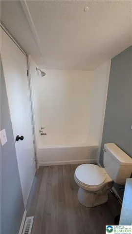 a white toilet sitting next to a bath tub