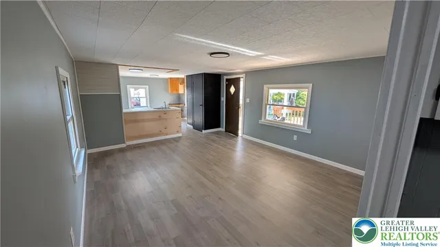 a view of an empty room with window and wooden floor