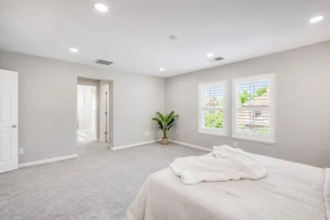 a view of a hallway with wooden floor and a bathroom