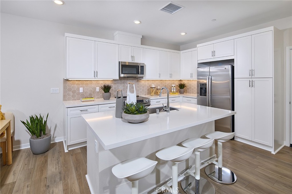 5911 Rockport Road Eastvale, CA 92880 - Photo 6 of 39 a kitchen with stainless steel appliances a table chairs refrigerator and microwave