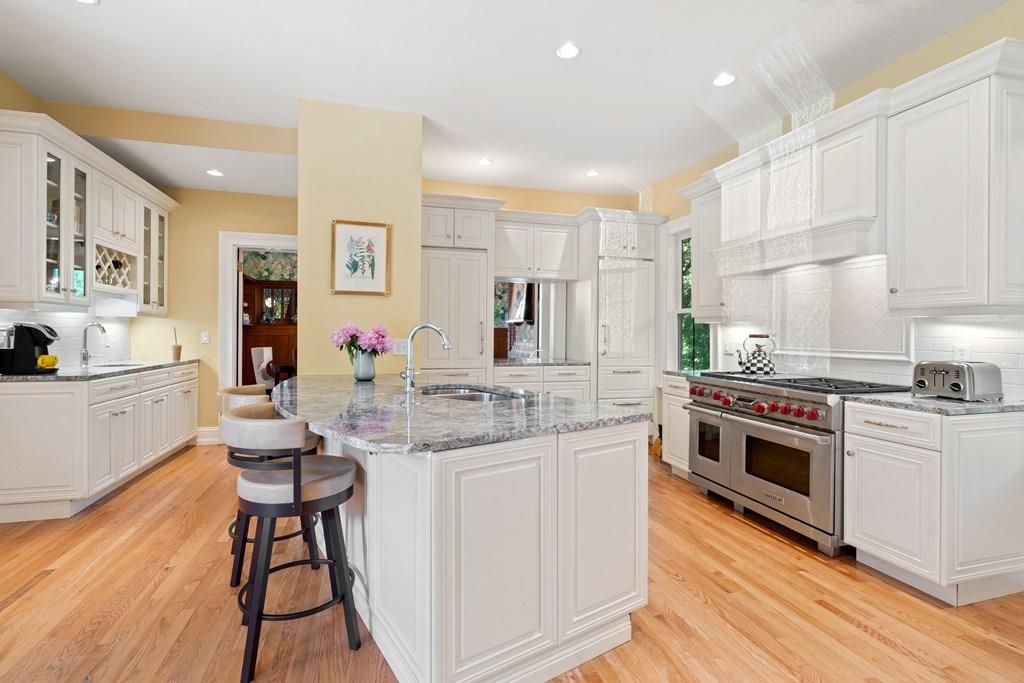 699 Boston Post Road Weston, MA 02493 - Photo 14 of 41 a kitchen with stainless steel appliances kitchen island granite countertop a stove a sink dishwasher and white cabinets with wooden floor