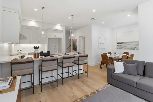 a living room with furniture kitchen view and a wooden floor