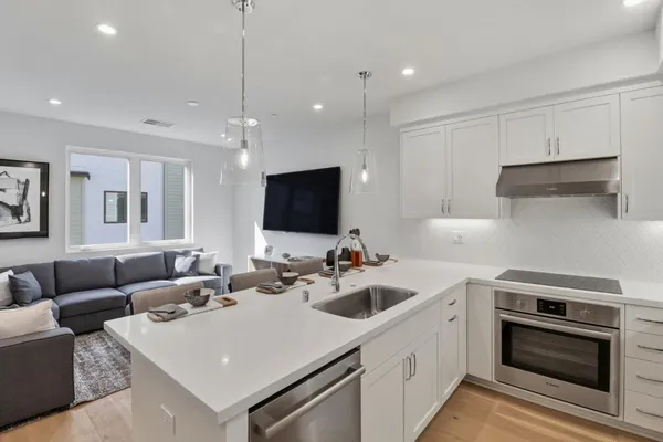a kitchen with stainless steel appliances a stove a sink a microwave a refrigerator and white cabinets