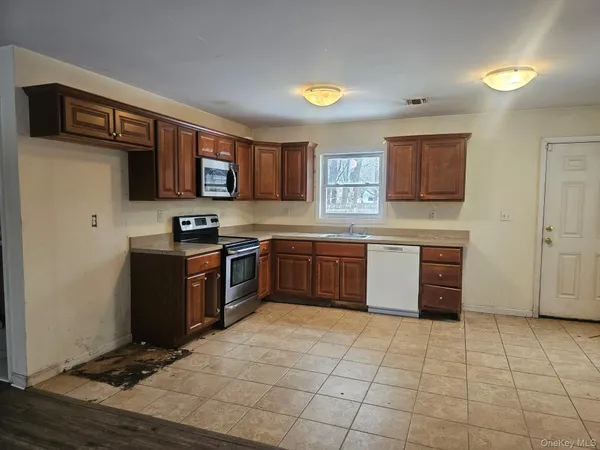 a kitchen with stainless steel appliances granite countertop a stove top oven a sink and a refrigerator