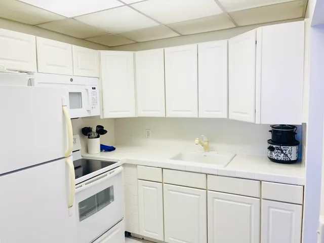 a kitchen with white cabinets and white appliances