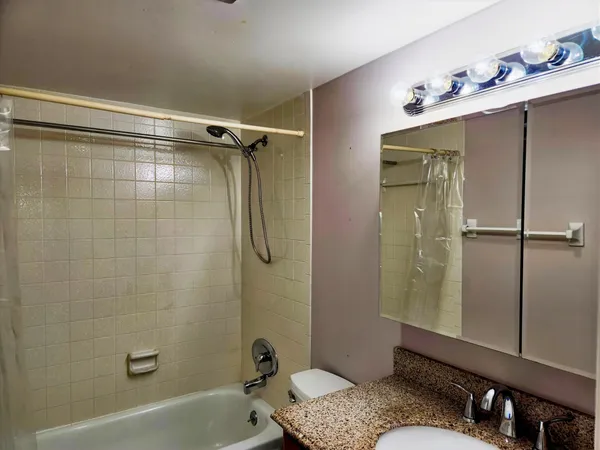 a bathroom with a granite countertop sink mirror bathtub and shower