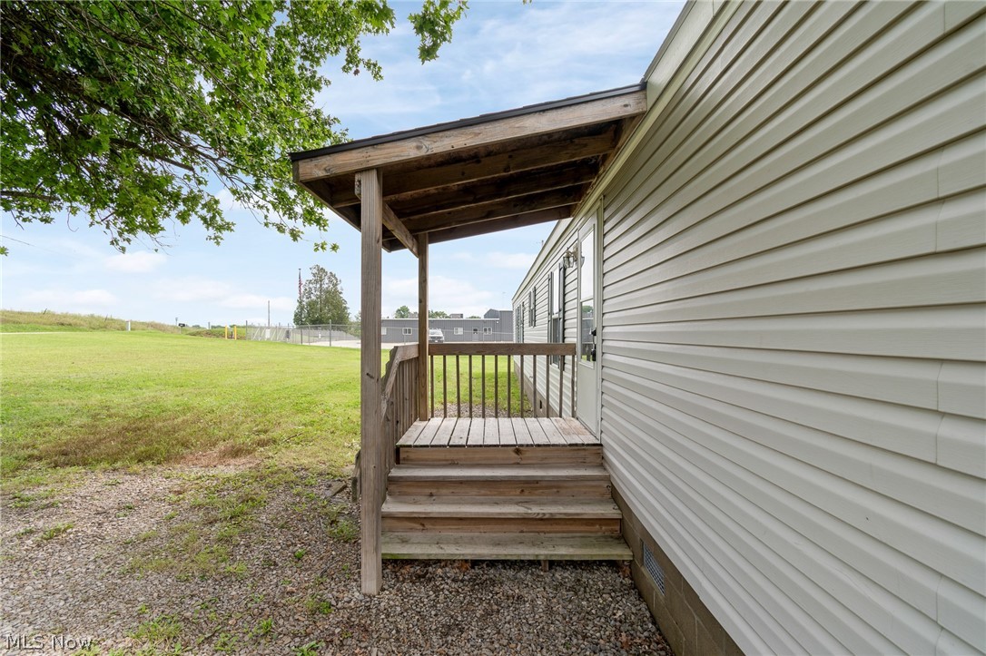 8472 Azalea Road Southwest Dennison, OH 44621 - Photo 6 of 35 Covered wood-plank porch with wood railings and steps, set against horizontal siding exterior