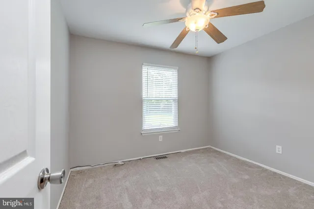 an empty room with a window and a chandelier fan