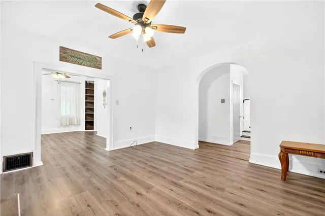 a view of an empty room with wooden floor fridge and a window