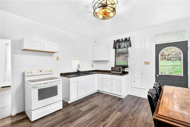 a kitchen with granite countertop a sink a stove and cabinets