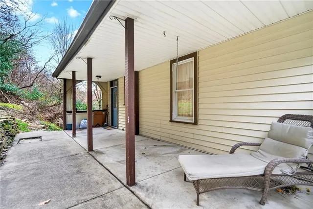 a view of a white house with a yard and lawn chairs under a large tree