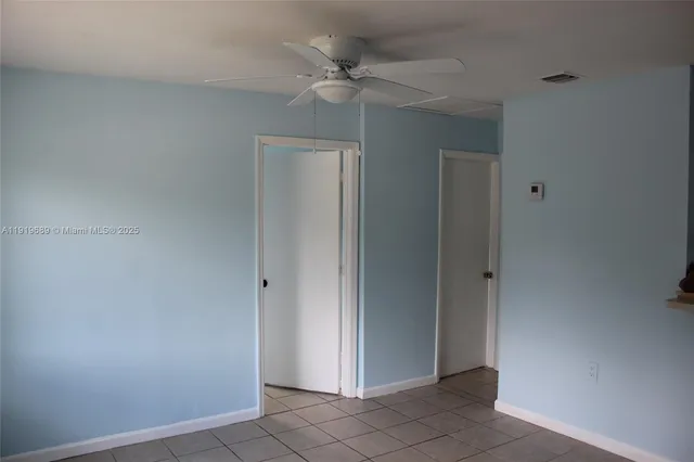 an empty room with a ceiling fan and carpet